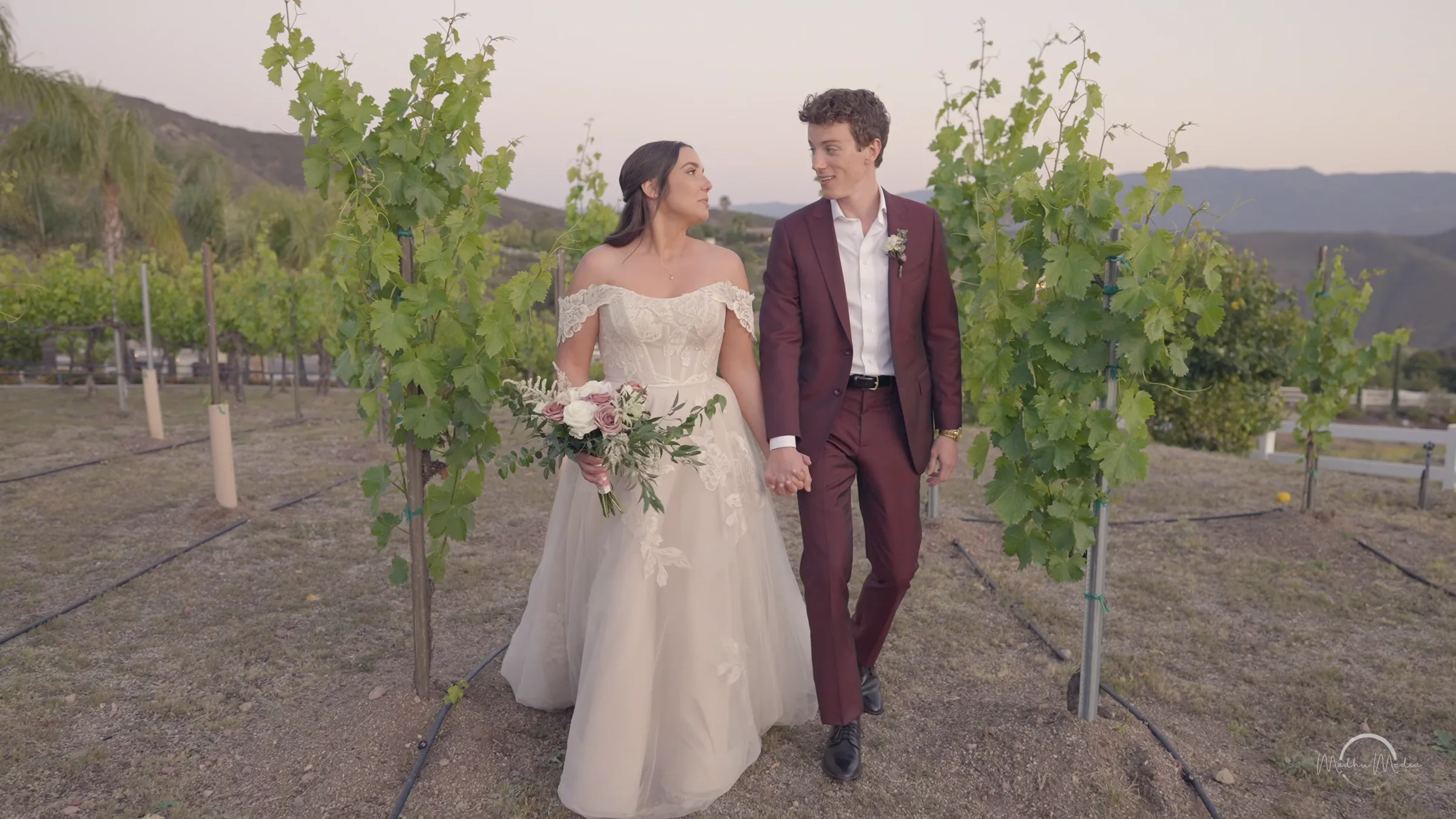 Caitlin and Ross walking between vineyard rows at their estate wedding
