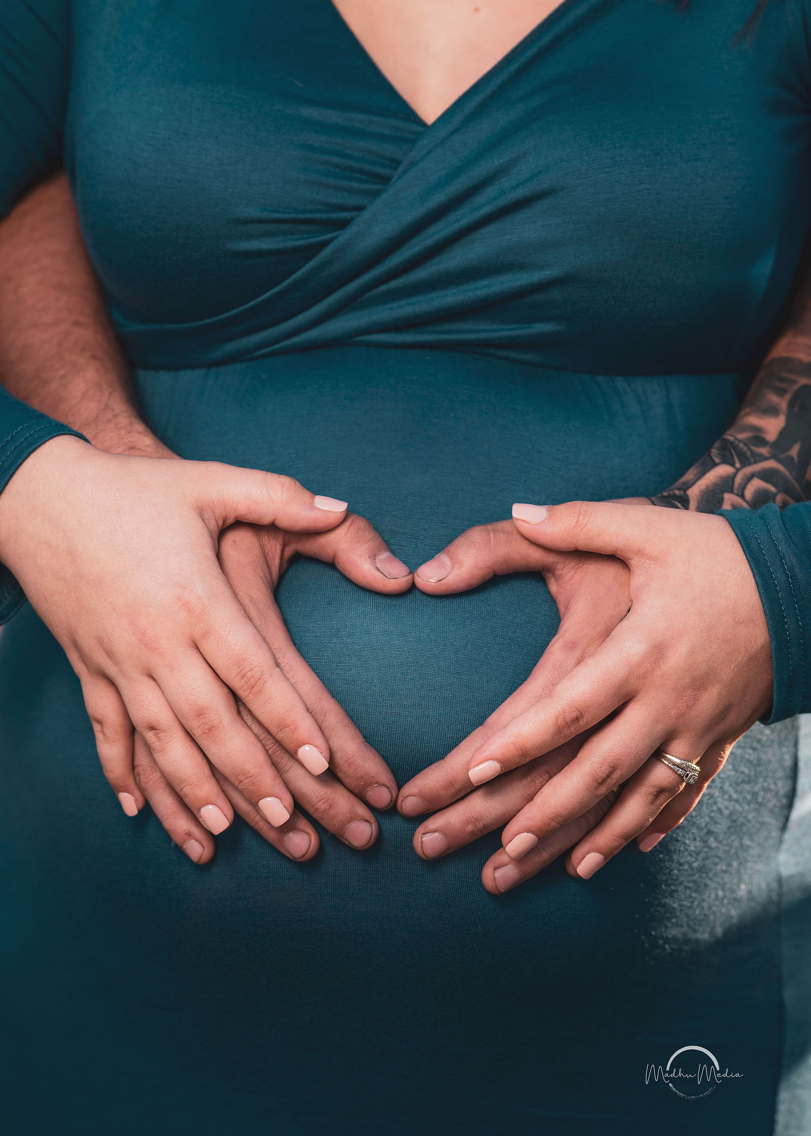 Their hands making a heart over the bump