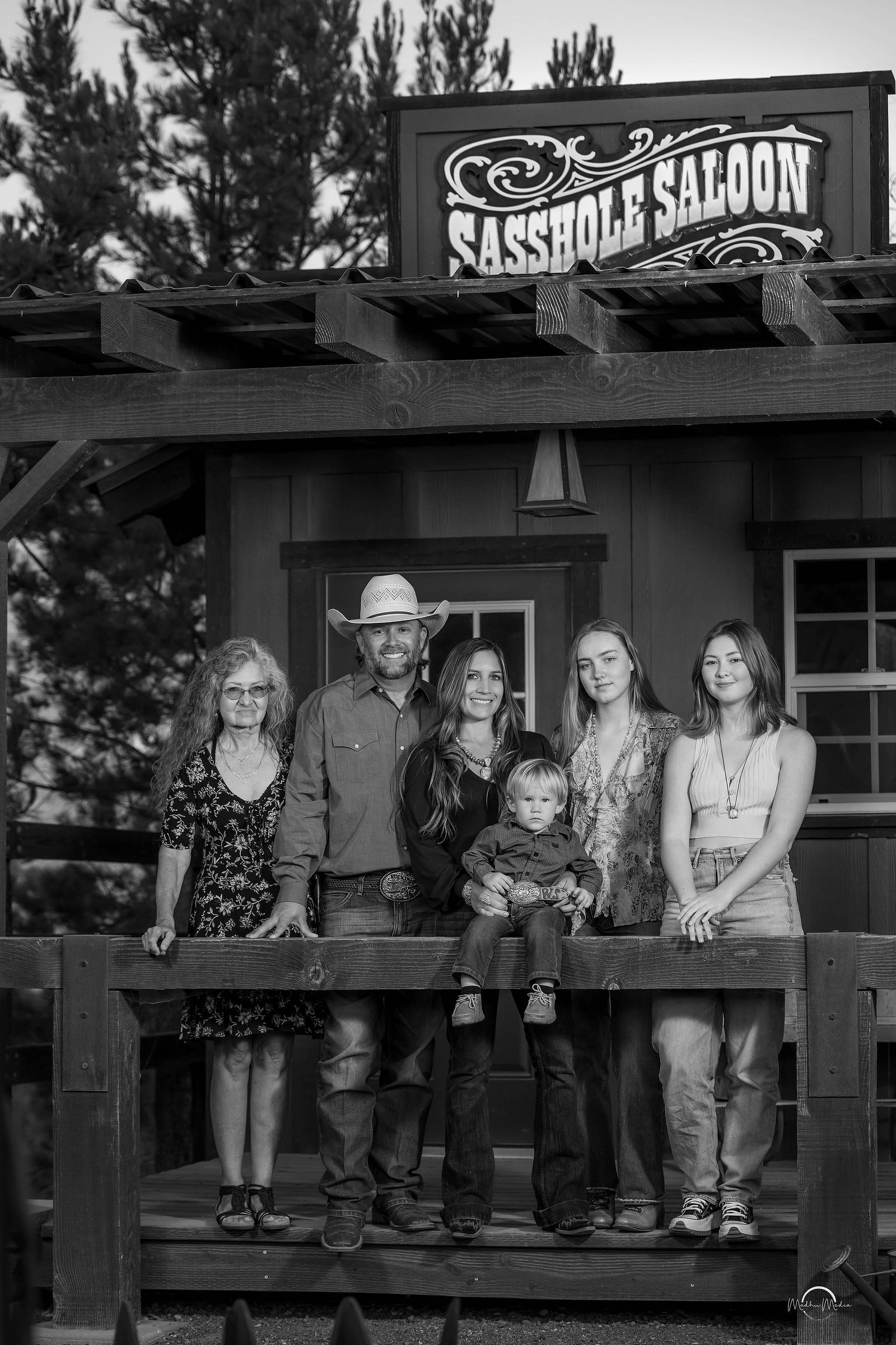 Three generations on the porch of an old western saloon, in black and white