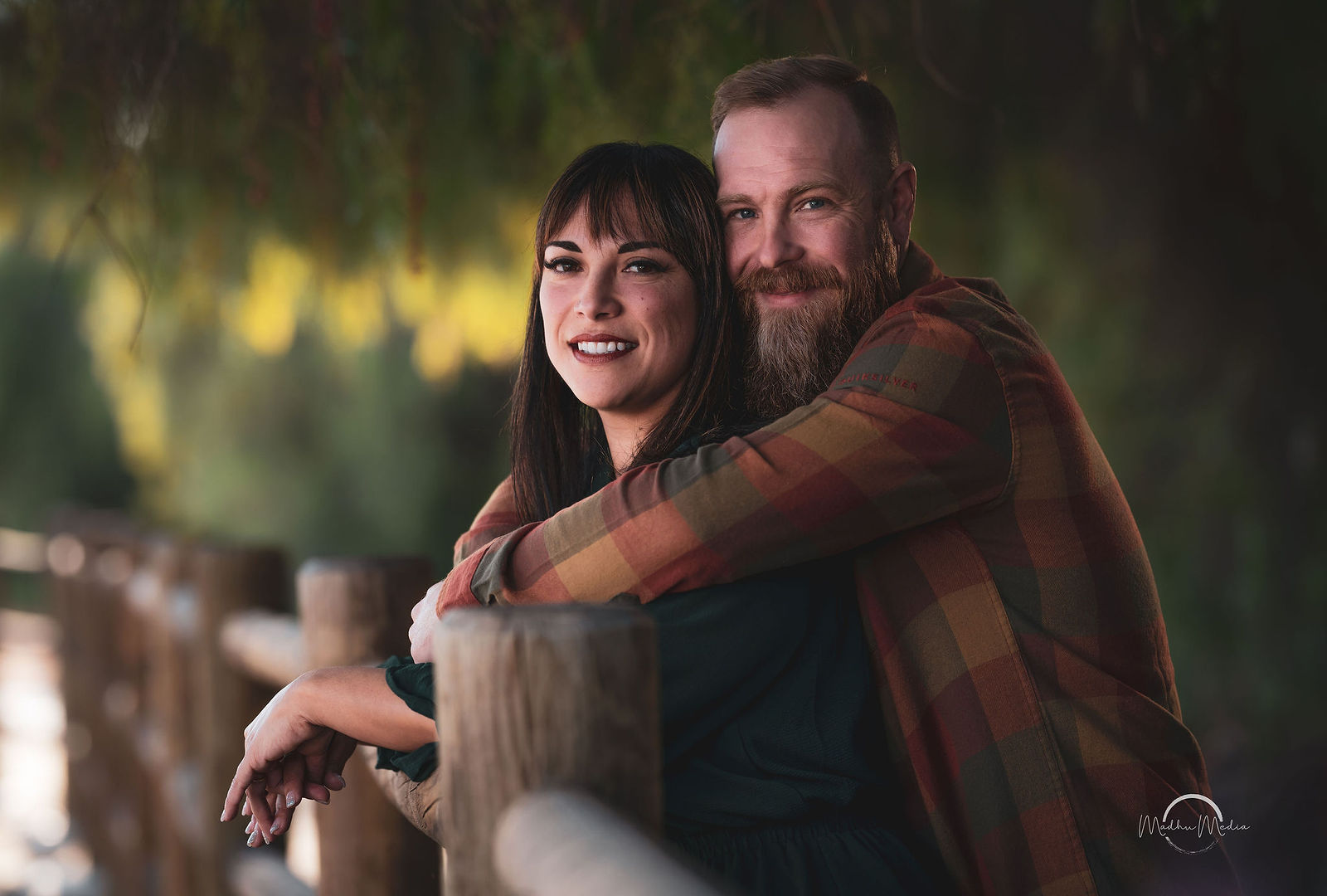 Couple leaning together at the rail fence in autumn plaid