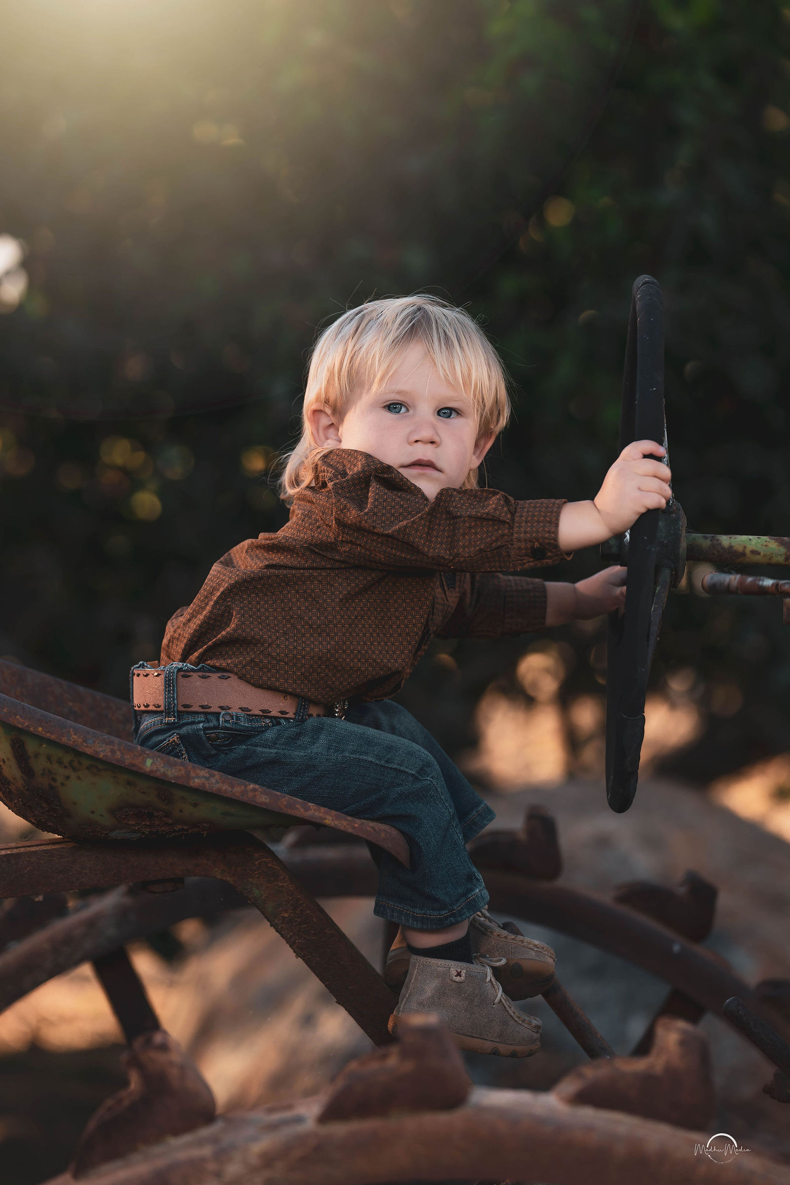 Toddler at the wheel of a rusted antique tractor