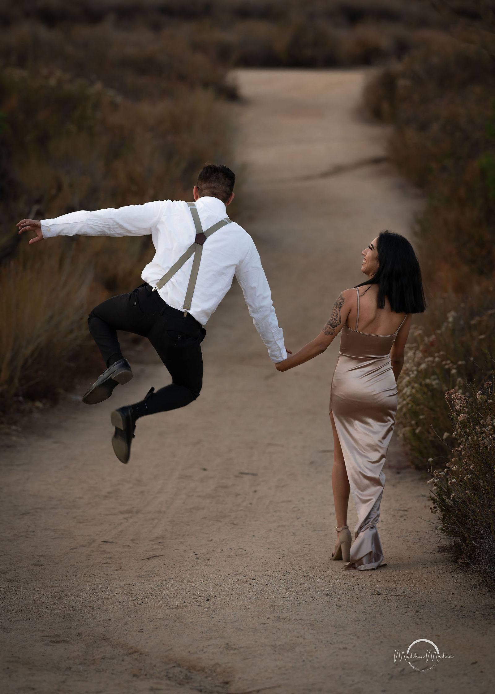 He clicks his heels mid-air while she leads him down the trail