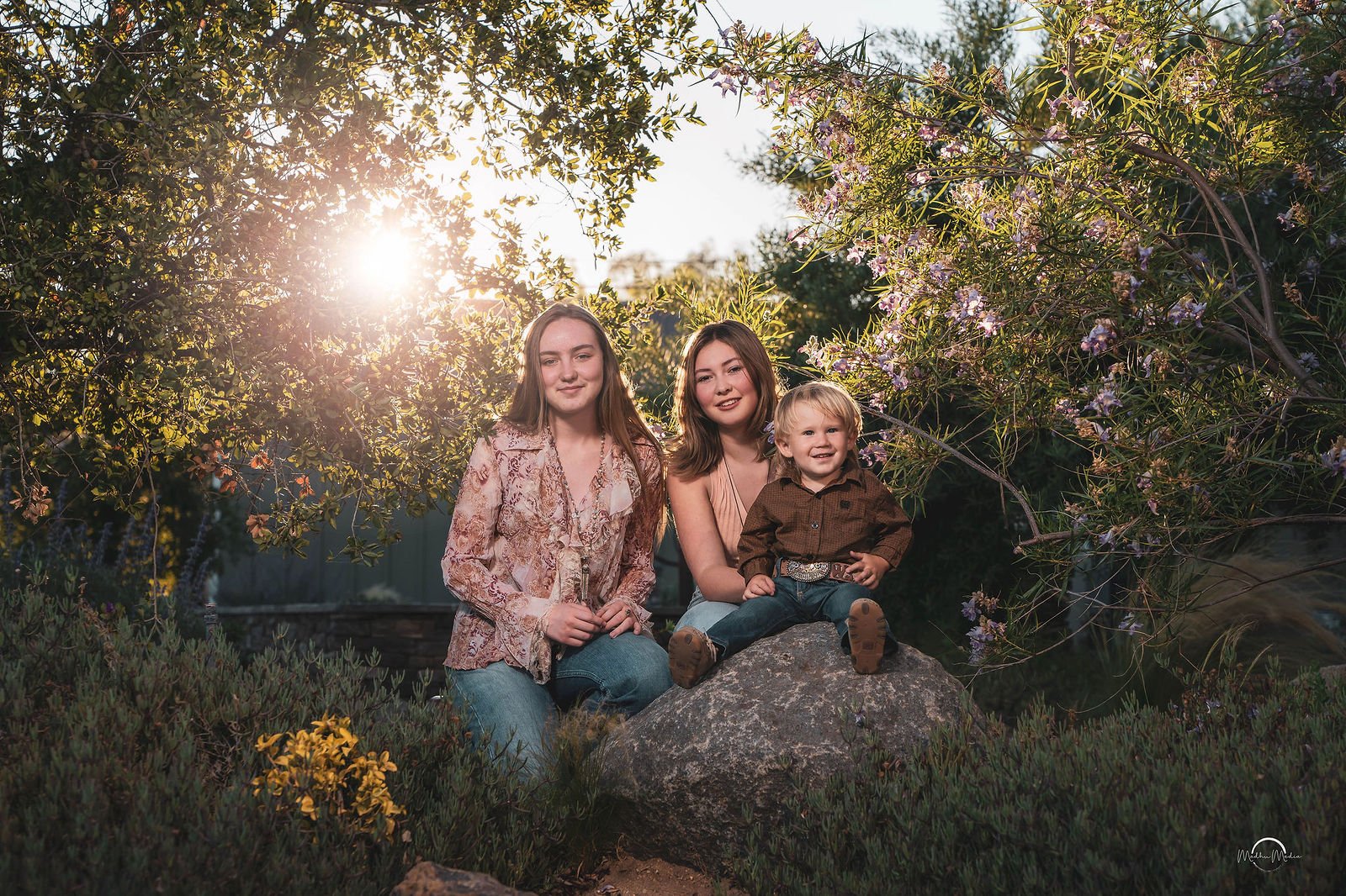The three kids together on a boulder under the evening sun