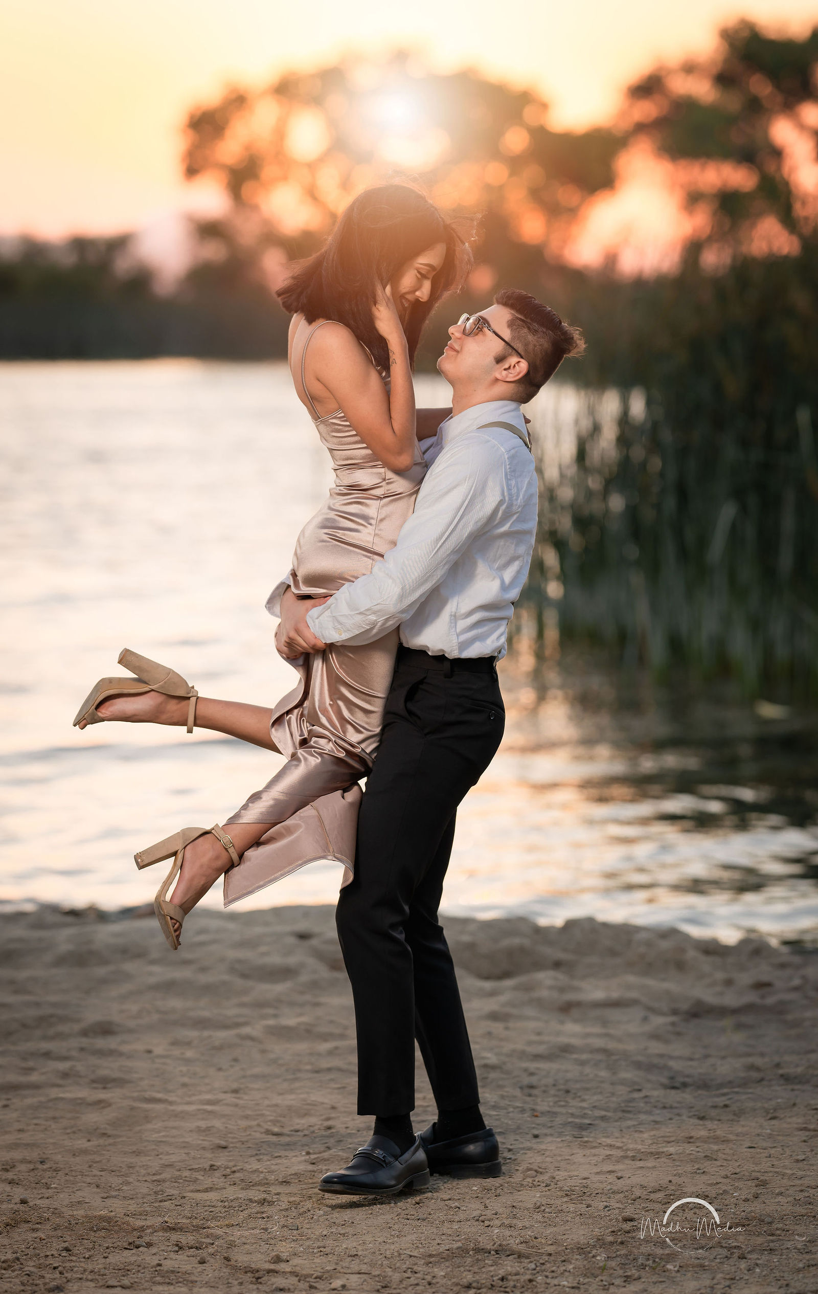 He lifts her off her feet on the lake shore at sunset