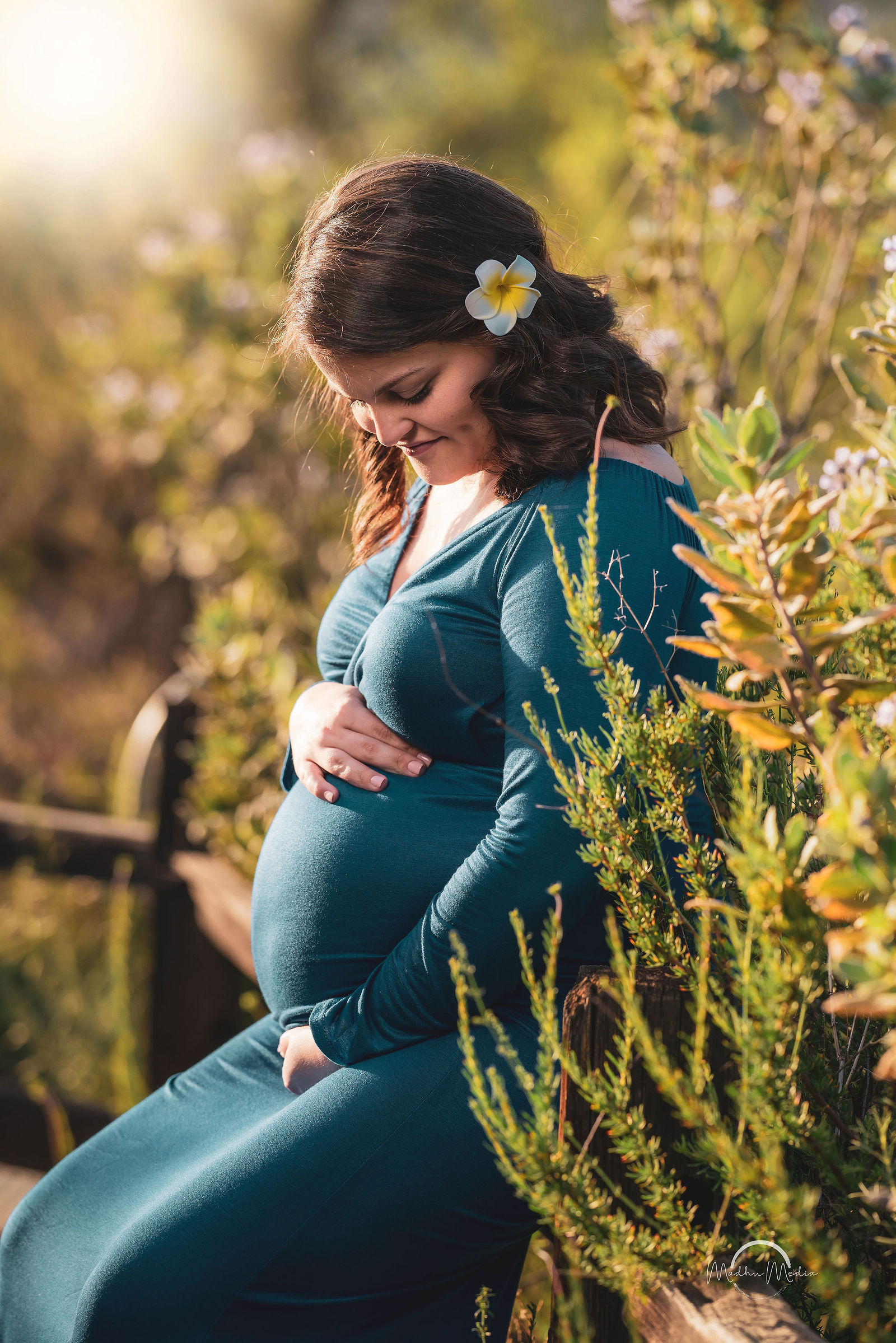 Maternity portrait in a teal dress, flower in her hair